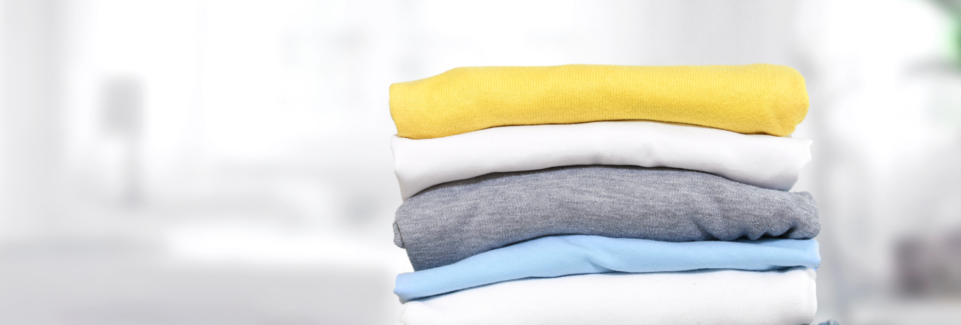 Stack Of Laundry With Yellow Shirt On Top 1920X650